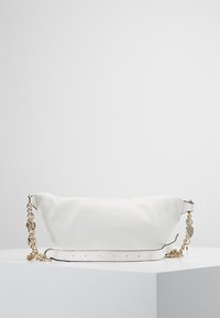 Valkoinen nahkalaukku, jossa on teksturoitu pinta, kullattu ketjumainen hihna, sileät yksityiskohdat ja pyöreä, pitkulainen muoto.