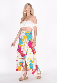 Hvid off-shoulder cropped top og en lang, farverig nederdel med blomstermønstre i pink, turkis og gul; har en sideslids.