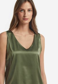 Zielona satynowa koszulka na ramiączkach z dekoltem w kształcie V i bez rękawów, o gładkiej fakturze i subtelnym połysku.