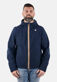 La giacca a vento navy con cappuccio presenta una zip gialla e bianca, un logo sul lato sinistro del petto ed è realizzata in un tessuto liscio e resistente all'acqua.