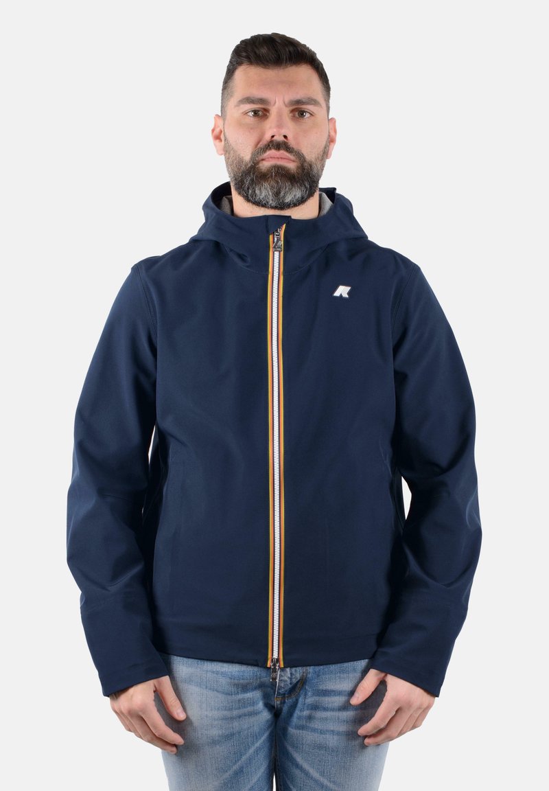 La giacca a vento navy con cappuccio presenta una zip gialla e bianca, un logo sul lato sinistro del petto ed è realizzata in un tessuto liscio e resistente all'acqua.