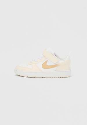 Adidași cu partea superioară din piele albă și accente bej. Căptușeală din plasă gri, șireturi albe și bretea cu velcro. Talpă de cauciuc cu crampoane texturate.