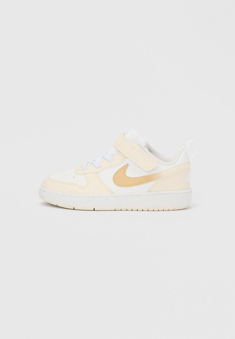 Αθλητικά παπούτσια με λευκό δερμάτινο επάνω μέρος και μπεζ λεπτομέρειες. Γκρι επένδυση από δίχτυ, λευκά κορδόνια και λουράκι με βέλκρο. Λαστιχένια σόλα με υφή στο πέλμα.