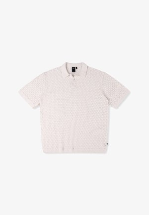 Kortermet polo skjorte i lys beige strikk. Har et teksturert diamantmønster, krage og knapplist.