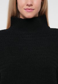 Musthave mustribaline särg, millel on kõrge kaelus ja lõtv istuvus. Lihtne, ühtlane värvi disain.