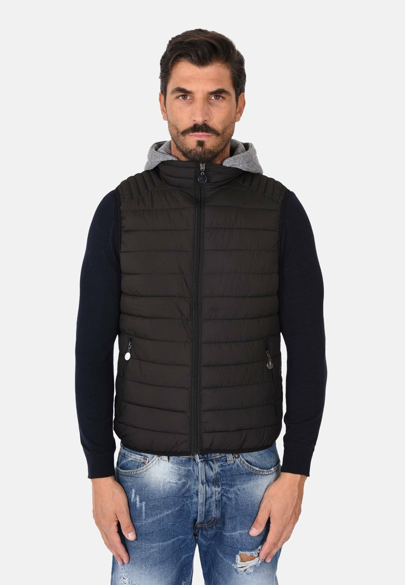 Gilet imbottito nero con chiusura a zip, fodera in felpa grigia e colletto a coste. Abbinato a jeans blu strappati. Design leggero e informale.