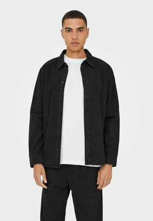 Schwarzes Hemd mit Knöpfen und Kragen, aus strapazierfähigem Stoff. Über einem weißen T-Shirt getragen, hat es eine bequeme Passform und Vorderknöpfe.