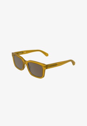 Lunettes de soleil rectangulaires translucides jaunes avec des verres foncés, marquage Calvin Klein Jeans sur les branches.