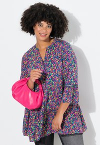 Tunic floreale colorato con orlo arricciato, maniche a tre quarti e scollo a V, abbinata a una borsa lucida rosa.
