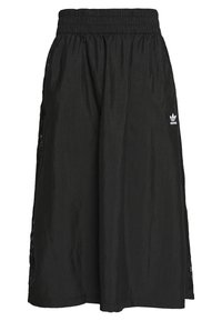 Svart midilång kjol gjord av lättviktsmaterial. Har en elastisk midjeband och sidoklyftor, med en liten vit Adidas-logga.