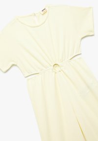 Vestido amarillo claro hecho de una tela texturizada, con mangas cortas, escote redondo y una cintura fruncida que presenta un acento circular.