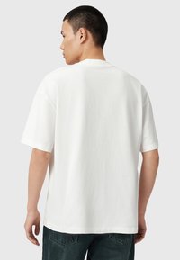 Hvid bomulds-T-shirt med en afslappet pasform, korte ærmer og rund halsudskæring. Glat tekstur, ingen synlige mønstre eller hardwaredetaljer.