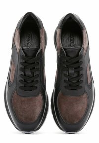 Des baskets en suède et cuir noir et marron présentent un bout arrondi, un laçage traditionnel et des panneaux texturés, avec une semelle en caoutchouc blanche.