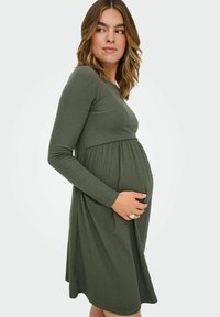 Äitiysmekko oliivinvihreästä ribbikankaasta, pitkät hihat, istuva vartalo, empire-vyötärö, kellotettu hame ja sileä pinta.