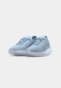Zapatillas deportivas azul claro con una parte superior de malla texturizada, suela de goma blanca y cordones planos. Presentan un sutil acento de logotipo en el lateral.