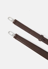 Brun læderrem med slankt design, sølv metalclips og en struktureret overflade. Har en løkke til justering og sikker fastgørelse.