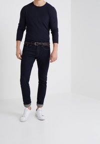 Tummansininen pitkähihaisen paita, tummat farkut, punottu ruskea vyö ja valkoiset lenkkarit, joissa kullanruskeat yksityiskohdat. Tiimalasimuotoinen siluetti, käännetyt farkunlahkeet.