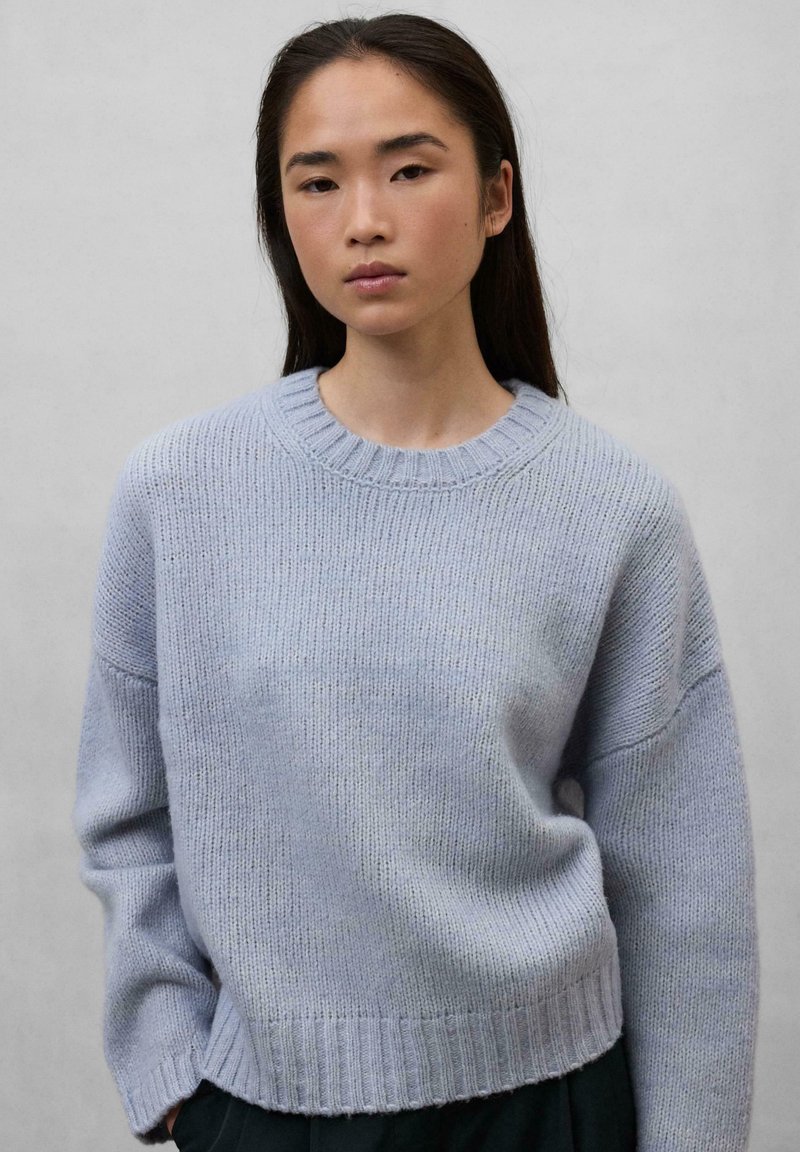Light blue knitted sweater with a round neckline, ribbed cuffs and hem, featuring a relaxed fit and smooth texture.