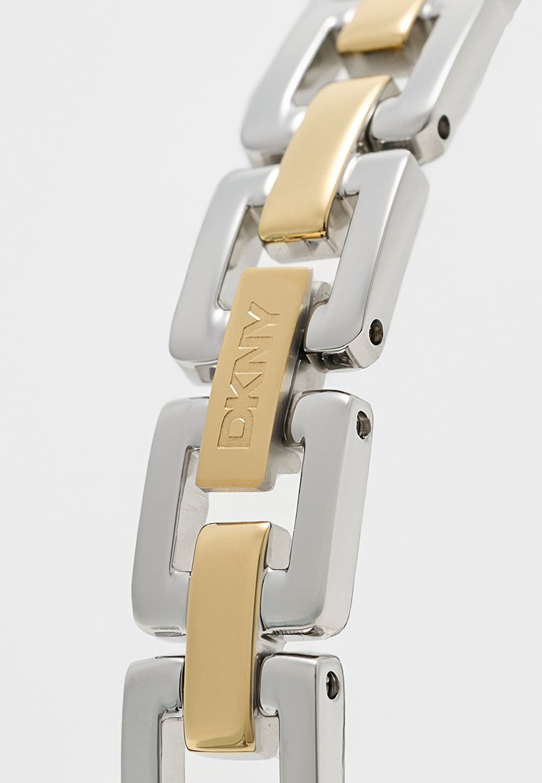 Bracciale in metallo argento e oro con maglie rettangolari. La maglia centrale presenta un'incisione DKNY. Texture liscia con una finitura mista.