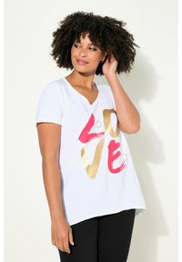 T-shirt blanc à manches courtes avec un col en V présentant un grand motif "LOVE" en rose et or, accompagné d'accents de smiley, avec une coupe décontractée.
