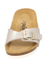 Sandal med slids i metallisk silver syntetmaterial, justerbar spänne och en tan-färgad vadderad fotbädd. Vit gummisul med texturerat grepp.