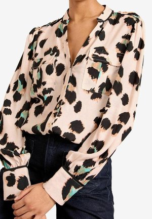 Bluzka z długim rękawem w beżowym kolorze bazowym z czarnymi, morsko-zielonymi i brzoskwiniowymi abstrakcyjnymi plamami, z zapinanymi na guziki kieszeniami na piersi i mankietami na rękawach.