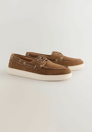 Braune Wildlederschuhe mit einer weißen Gummisohle, Schnürdesign, metallischenösen und kontrastierenden Nähten entlang der Kanten.