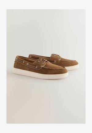 Hnědé semišové boty s bílou gumovou podrážkou, šněrovací design, kovové očka a kontrastní prošívání podél okrajů.