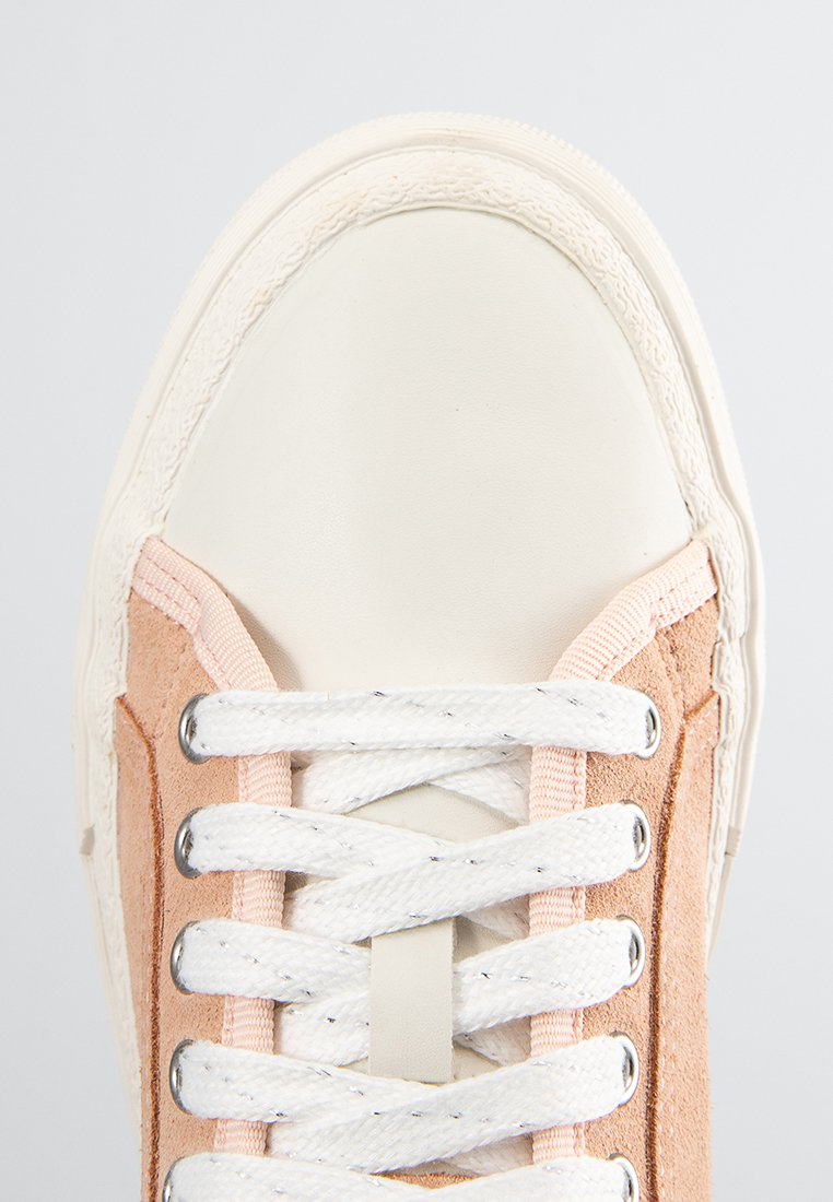 Zapatillas de lona en melocotón pastel y crema. Presentan una puntera redondeada, paneles laterales de ante texturizado y cordones blancos con ojales de metal.