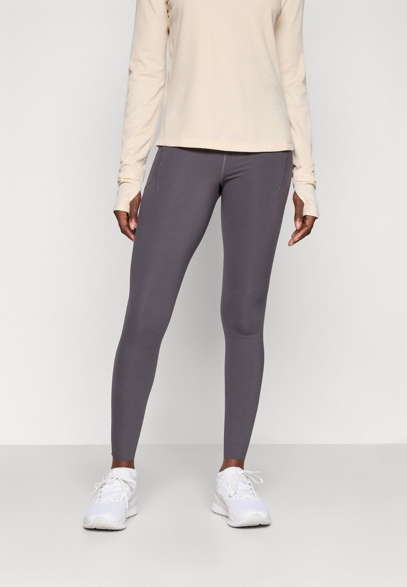 Grå leggings laget av stretchy stoff, med en tettsittende design og subtile sømdetaljer, kombinert med en langermet beige topp.