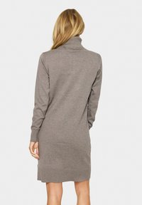 Abito maglione taupe a maniche lunghe con colletto alto, texture a coste e design aderente, che termina sopra il ginocchio.