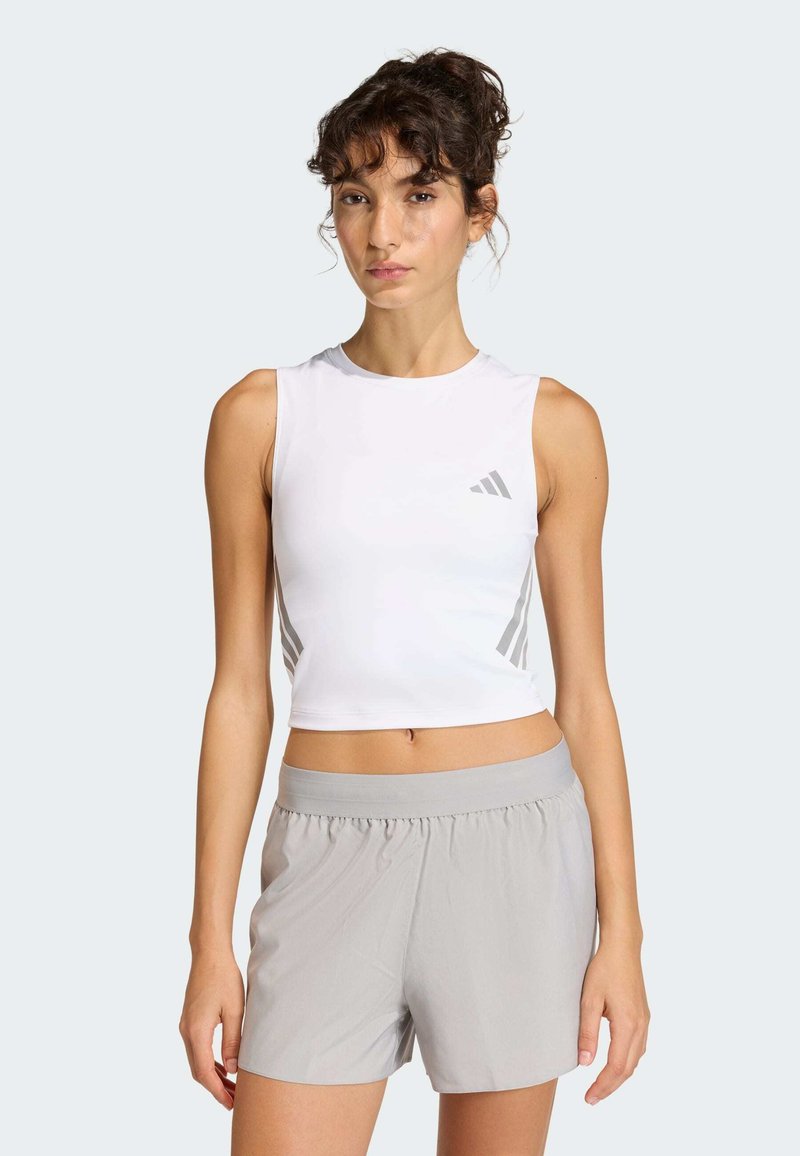 Biely bezrukávový crop top so sivými akcentmi a logom, v kombinácii so svetlosivými športovými šortkami s elastickým pásom.