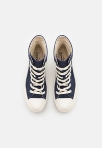 Sneaker alte in tela blu con punte e lacci in gomma bianca, dotate di una fodera interna beige e del logo sulla soletta.