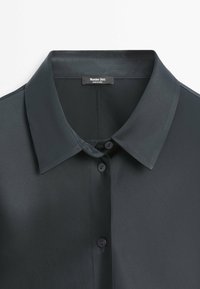 Chemise noire à col avec des boutons sur le devant et une étiquette "Massimo Dutti" cousue à l'intérieur de l'encolure.