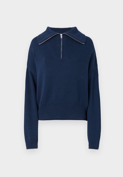 Marineblå strikket pullover med lynlås i halsen og bred krave, der har et struktureret mønster samt ribbetrukket kant og ærmer.