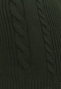 Mörkgrön stickad tyg med vertikal ribbning och texturerade flätade mönster, vilket ger ett tjockt och lager-på-lager utseende.