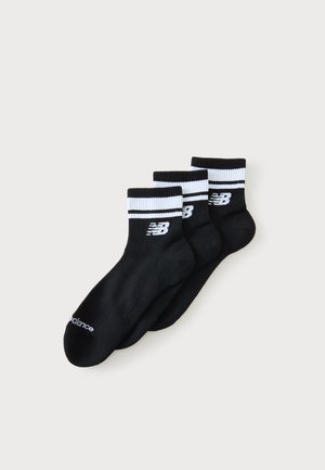 Drei schwarze Knöchelsocken mit weißen, gerippten Bündchen, die schwarze Streifen und ein weißes New Balance-Logo auf jedem Bündchen zeigen.