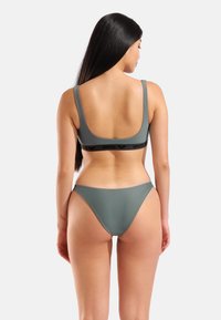 Conjunto de bikini gris con un top de diseño minimalista y tirantes anchos, acompañado de una braguita de corte alto a juego. Hecho de tela suave y elástica.