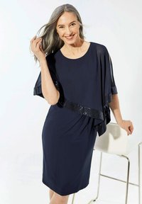 Navy Kleid mit einem geschichteten Cape-Design, das mit einem Paillettenbesatz am Saum verziert ist. Glattes Material mit einer figurbetonten Silhouette.
