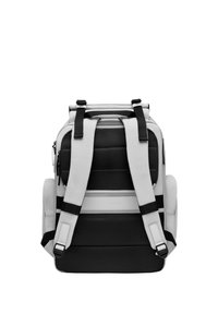 Un sac à dos noir et blanc avec des bretelles rembourrées, un panneau texturé et des poches zippées. Présente une forme structurée et rectangulaire.