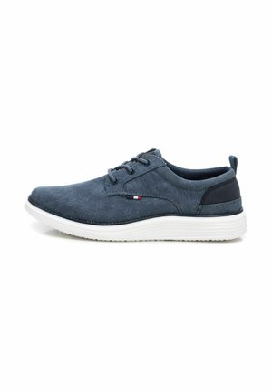 Zapatilla de tela en color navy con un upper suave y texturizado, punta redonda, diseño de cordones y suela blanca en contraste. Presenta un pequeño detalle con el logo.