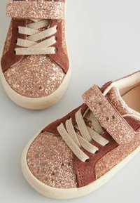 Glänzende rose-goldene Sneaker mit braunen Wildlederakzenten, strukturiertem Glitzer-Obermaterial, beigen Schnürsenkeln und einem Klettverschluss für sicheren Halt.