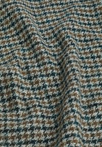 Tissu en laine avec un motif pied-de-poule en marron, bleu sarcelle, noir et blanc, montrant des plis texturés et des fibres douces.