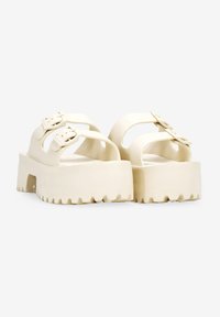 Sandali platform in beige chiaro con due fibbie regolabili, design con punta aperta, suola spessa e testurizzata, e soletta contornata.