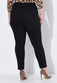 Zwarte stretchlegging met een textuur, voorzien van een hoge tailleband en zijkanten. Gecombineerd met hoge hakken met luipaardprint.