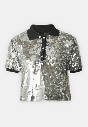 Skraćena polo majica s srebrnim šljokicama, crnim ovratnikom i placketom s gumbima. Kratki rukavi i teksturirana površina s efektom sjaja.