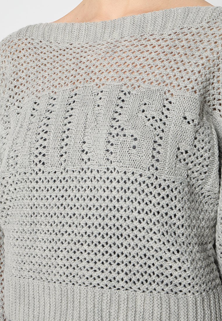 Hellgrauer Strickpullover mit lockerer Maschenstruktur, ausgestattet mit einem strukturierten Muster und einem weiten Ausschnitt. Texturiertes Rippenmuster am Saum und an den Ärmeln.