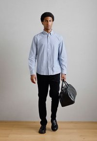  Ριγέ πουκάμισο με κουμπιά, μαύρο παντελόνι και μαύρη δερμάτινη τσάντα. Λείο ύφασμα, κομψή εφαρμογή και εντυπωσιακές μαύρες λεπτομέρειες. Απλό φόντο.