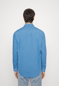 Camicia azzurro chiaro con colletto, in tessuto testurizzato, maniche lunghe e orlo arrotondato, dotata di polsini a bottone e finitura liscia.