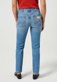 Vaqueros de mezclilla azul claro con un ajuste slim, que cuentan con bolsillos traseros con costura en zigzag y una etiqueta de cuero en el bolsillo derecho.